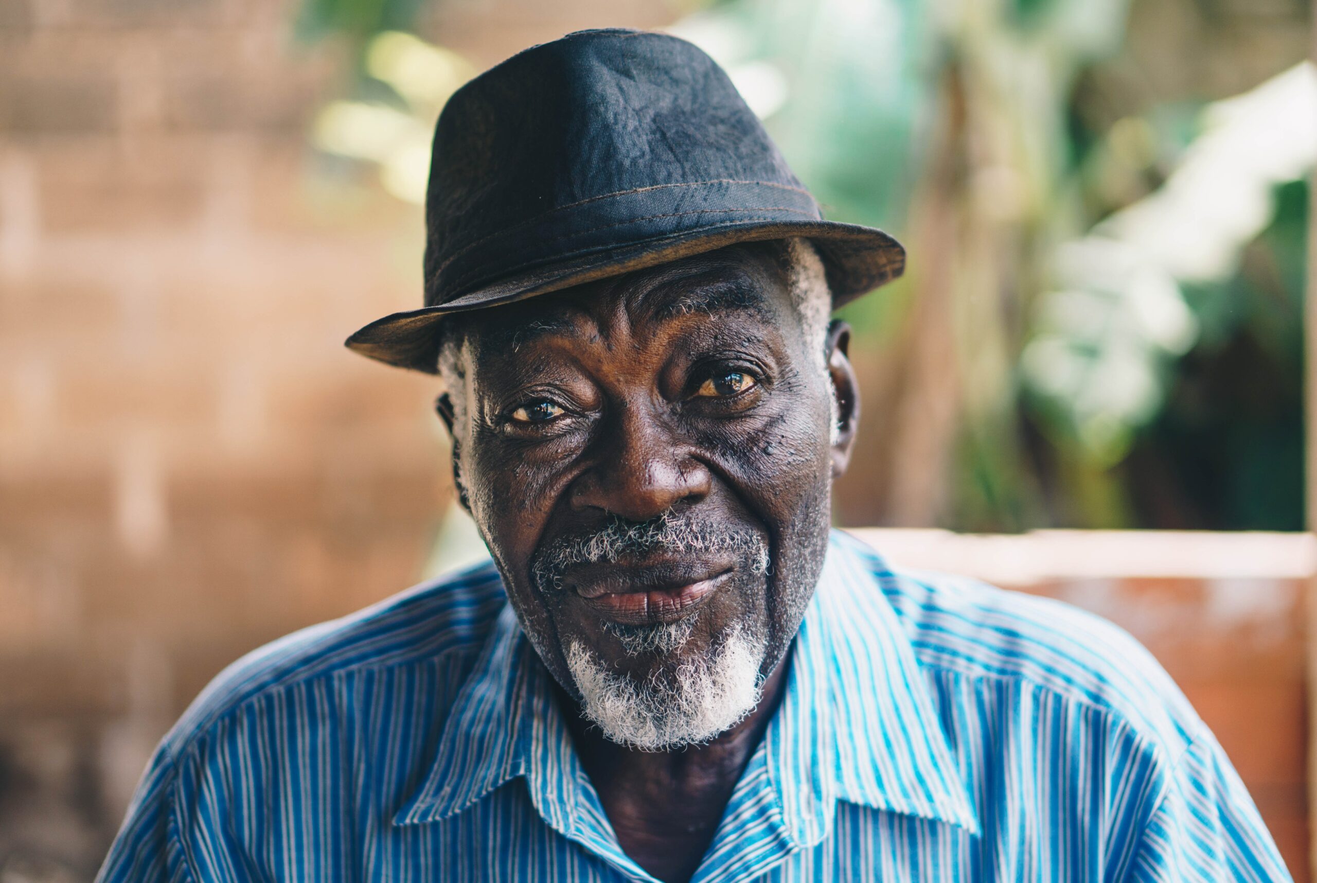 older black man wearing a hat and blue shirt.